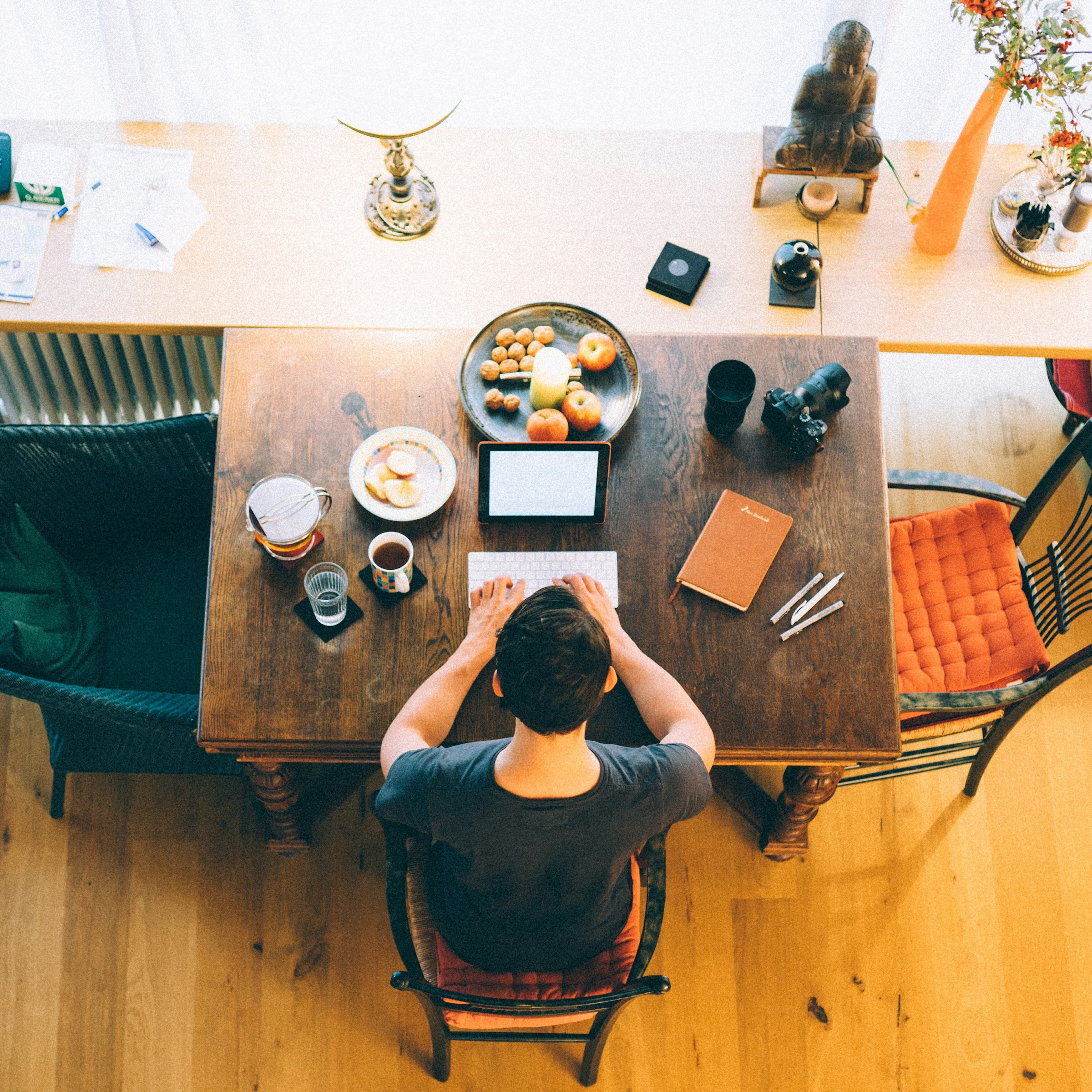 Overhead view of an author working at a wooden desk with notebook and tablet