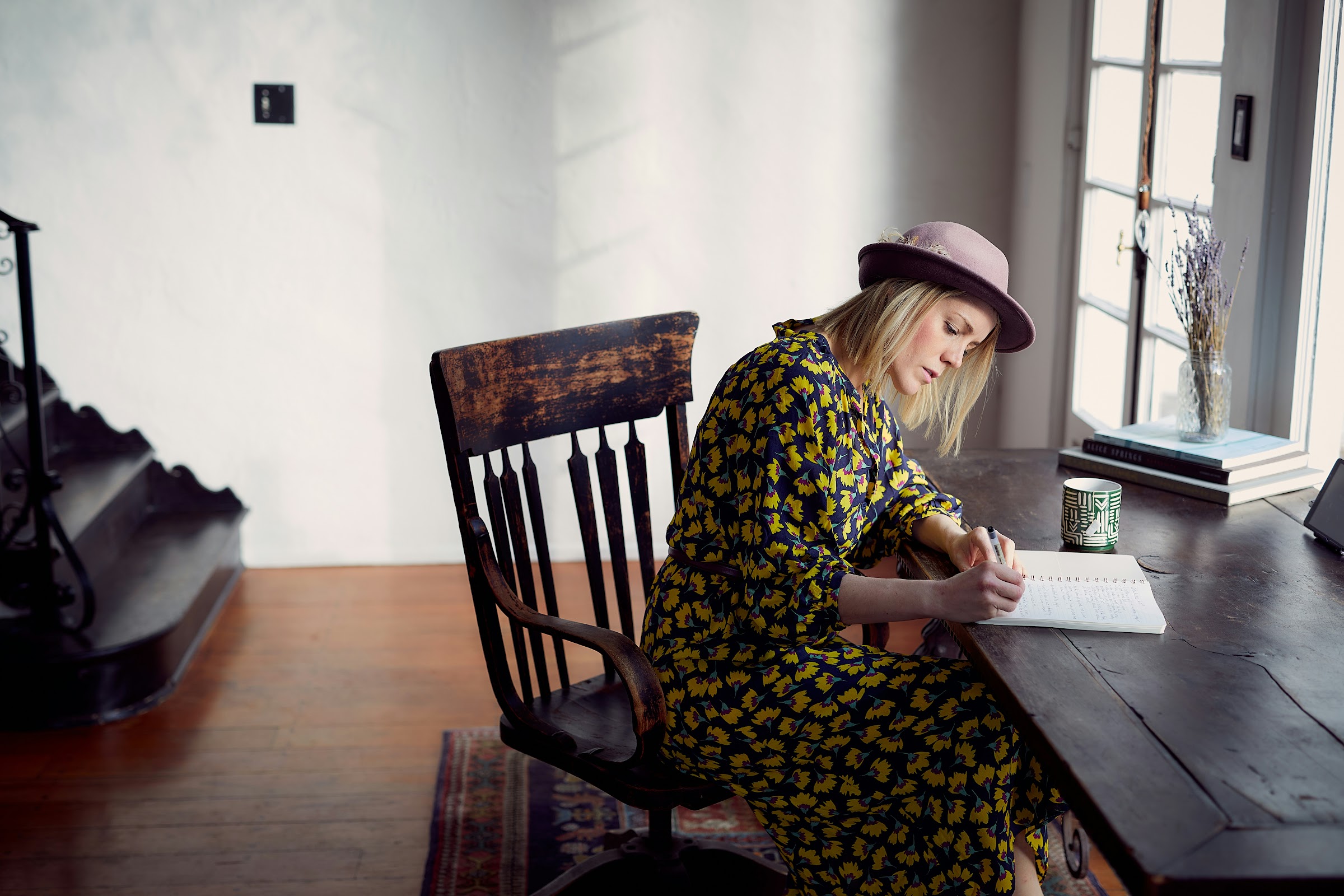 A writer at a wooden desk, drafting longhand by a sunlit window